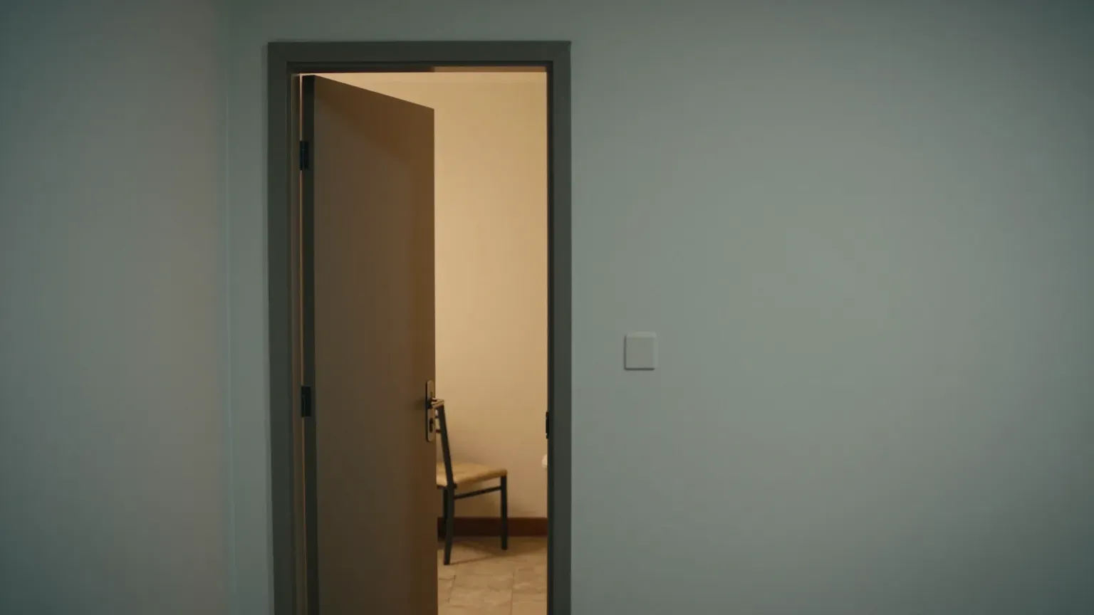 An open door with warm light spilling into a hallway